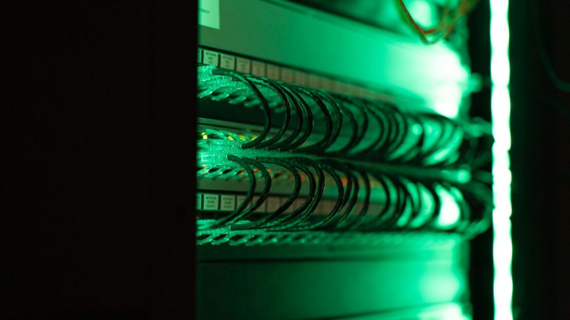 Close-up of a server rack with green-lit network cabling inside a server room