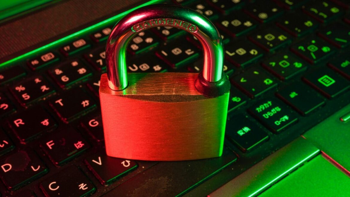 Red padlock resting on a backlit black computer keyboard representing data security