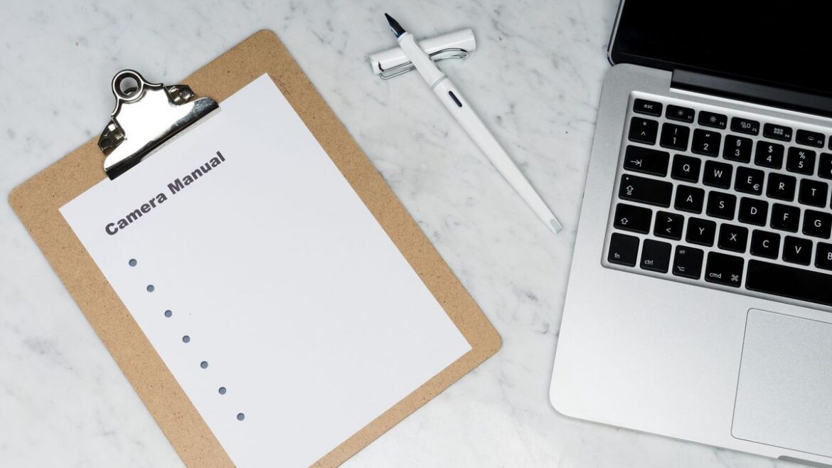 Top-down marble desk with laptop clipboard checklist and pen